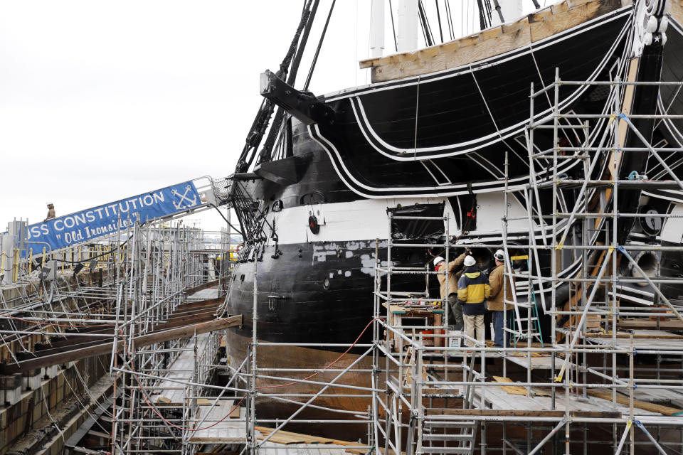 Men work on the hull of the USS Constitution in dry dock as restoration continues, Wednesday, April 5, 2017, at the Charlestown Navy Yard in Boston. The ship enters dry dock for below-the-waterline repairs every 20 years. The world's oldest commissioned warship afloat, is scheduled to return to the waters in late July. (AP Photo/Elise Amendola)