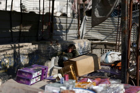 A boy rests while selling goods on a street in Douma, Syria February 3, 2016. REUTERS/Bassam Khabieh