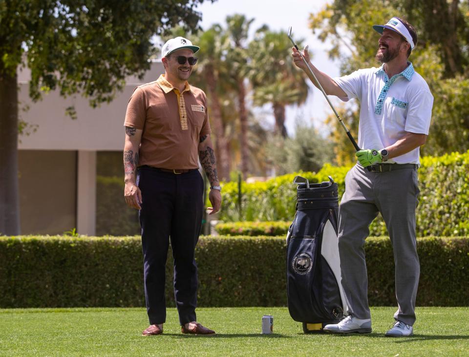Event organizer Adam Hawk shares a laugh with a participant as he picks up one of the vintage irons required for play from the sixth tee during the 16th annual Nation Desert Classic at Indian Wells Country Club in Indian Wells, Calif., Saturday, May 4, 2024.