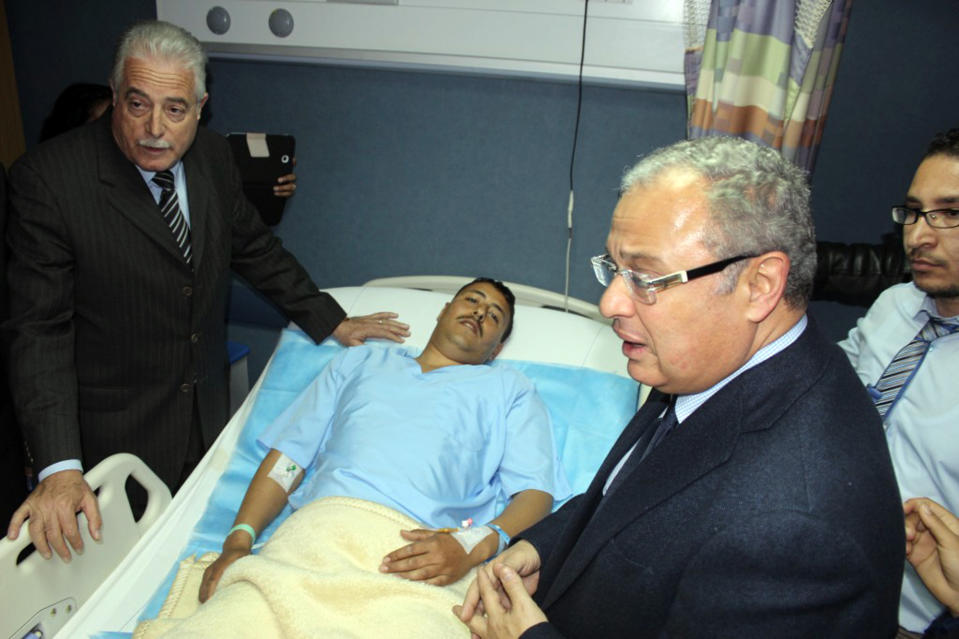 In this Sunday, Feb. 16, 2014 photo released by the Office of the South Sinai Governor, shows the Governor of South Sinai, Major General Khaled Foda, left, and Egyptian Minister of Tourism Hesham Zazou, second right, visit an unidentified Egyptian who was wounded in an explosion as a bus attempted to travel into Israel from Egypt near the Taba border crossing on Sunday, at a hospital in Sharm el-Sheik, South Sinai, Egypt. An explosion tore through a bus filled with South Korean sightseers in the Sinai Peninsula on Sunday, killing at least four people and raising fears that Islamic militants have renewed a bloody campaign to wreck Egypt's tourism industry. The bombing near the tip of the Red Sea's Gulf of Aqaba was the first attack against tourists in Sinai in nearly a decade. (AP Photo/Office of the South Sinai Governor )