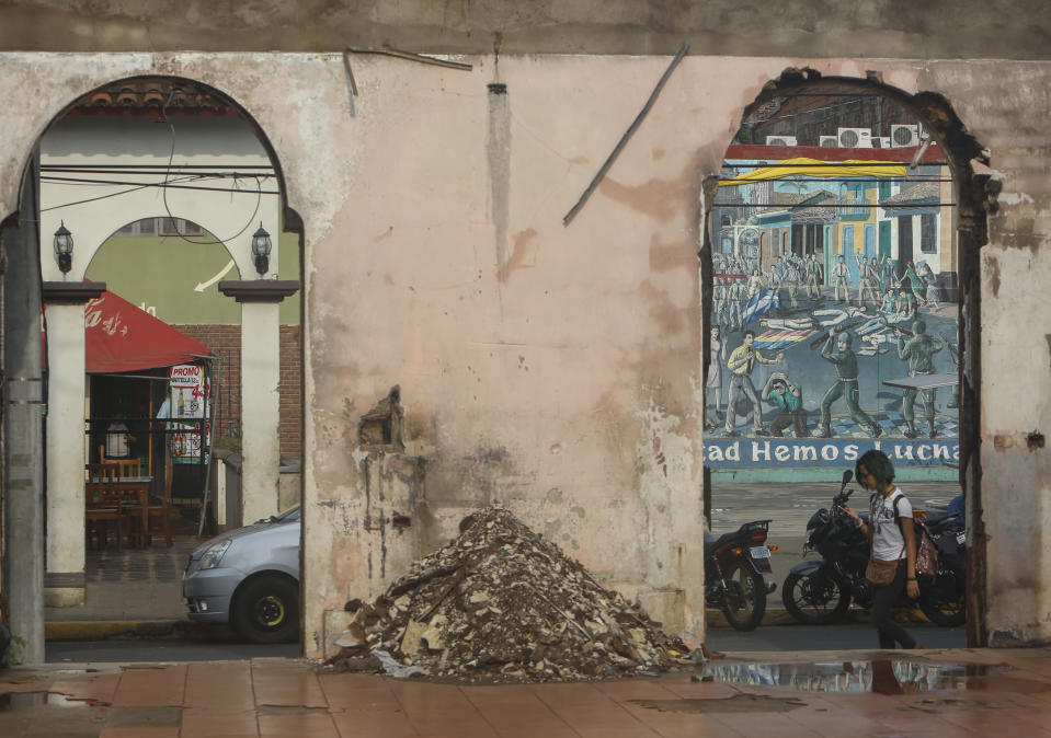 A woman walks past the gutted remains of Nicaragua's National University building in Leon, Nicaragua, Tuesday, Sept. 11, 2018. The university building, a Sandinista bastion, was burned down during the protests that erupted in April, against the government of President Daniel Ortega. (AP Photo/Alfredo Zuniga)