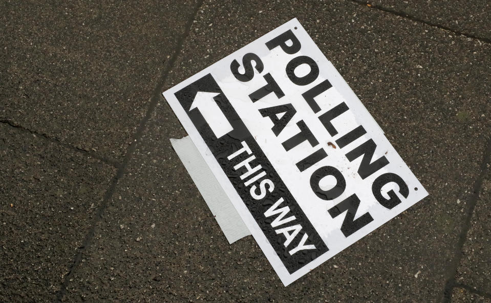 A polling station signpost lies on the pavement, in Twickenham, England, Thursday, Dec. 12, 2019. British voters are deciding who they want to resolve the Brexit conundrum in an election seen as one of the most important since the end of World War II.  (AP Photo/Frank Augstein)