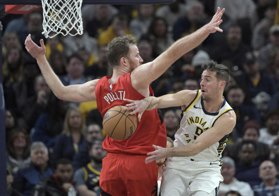 Indiana Pacers guard T.J. McConnell passes the ball around Toronto Raptors center Jakob Poeltl during the second half of an NBA basketball game Wednesday, Nov. 22, 2023, in Indianapolis. (AP Photo/Marc Lebryk)