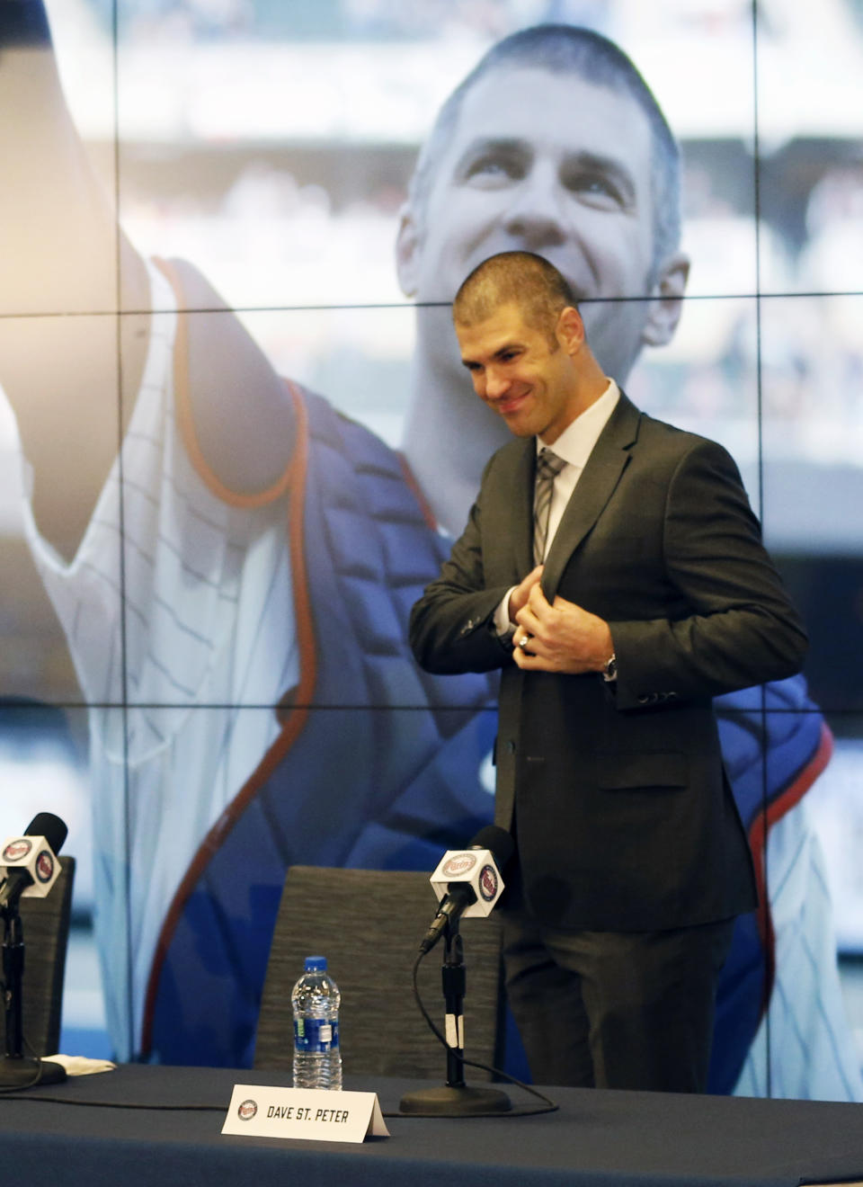 Minnesota Twins' Joe Mauer takes the stage in front of a photo of him acknowledging fans at the last game of the season Sept. 30, as he arrived for his baseball retirement news conference Monday, Nov. 12, 2018, in Minneapolis, after 15 major league seasons, all with the Twins. (AP Photo/Jim Mone)