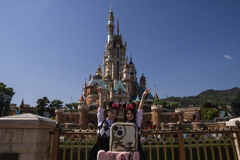 Visitors pose for photographs in front of the Castle of Magical Dreams at Disneyland Resort in Hong Kong, Monday, Nov. 20, 2023. (AP Photo/Louise Delmotte)