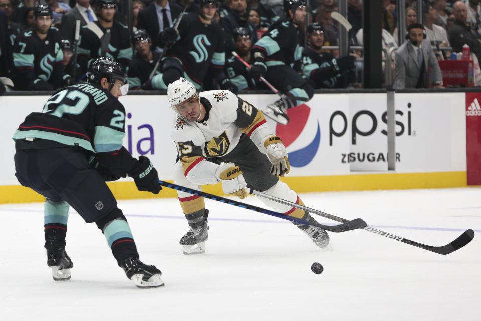Vegas Golden Knights defenseman Alec Martinez and Seattle Kraken right wing Oliver Bjorkstrand reach for the puck during the second period of an NHL hockey game Saturday, Oct. 15, 2022, in Seattle. (AP Photo/Jason Redmond)