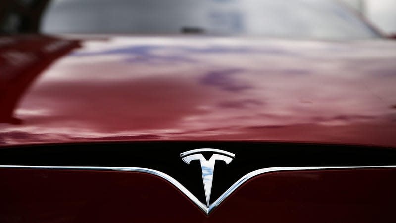 Closeup of a Tesla badge on a red Model S