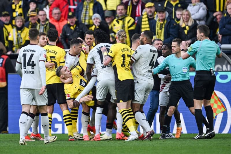 Players from both teams form a pack, Dortmund's Nico Schlotterbeck goes down after a scuffle with Leverkusen's Victor Boniface during the German Bundesliga soccer match between Borussia Dortmund and Bayer Leverkusen at Signal Iduna Park. Federico Gambarini/dpa