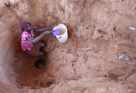 A woman fetches drinking water from a well along a dry Chemumvuri river near Gokwe, Zimbabwe, May 20, 2015. REUTERS/Philimon Bulawayo