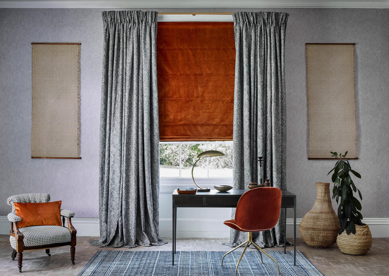  A living room with velvet orange roman blind and black and white patterned curtains. 