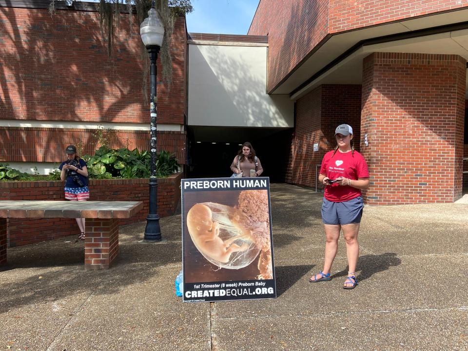 A member of the traveling Created Equal organization stands beside one of the group's anti-abortion displays in UF's Turlington Plaza on March 10, 2023.