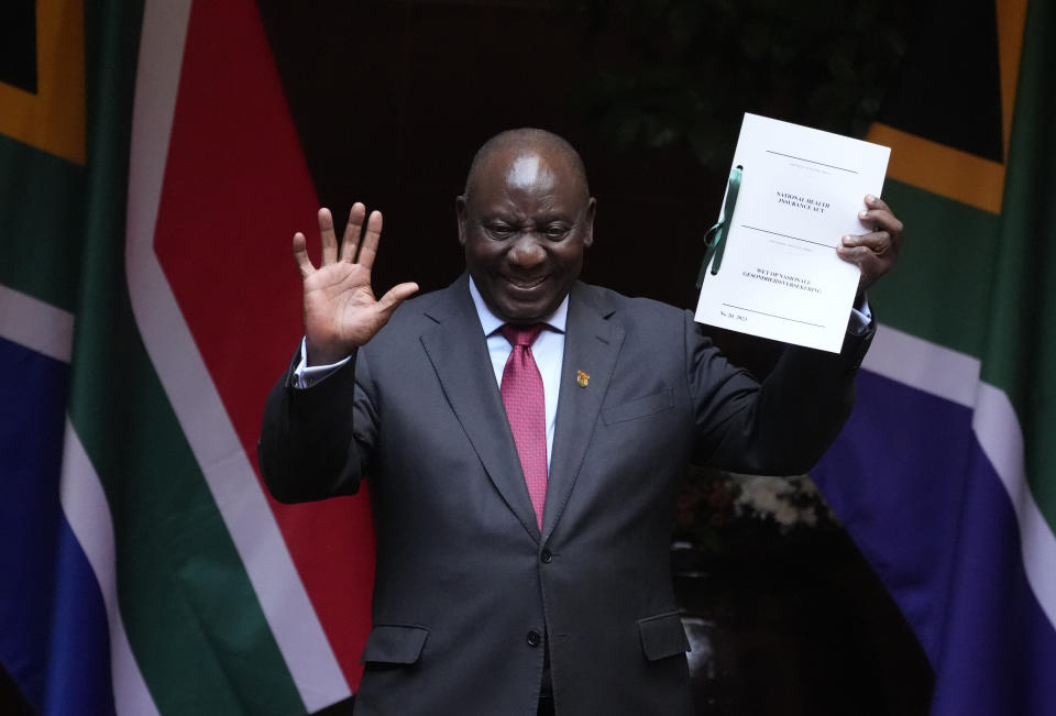 South African President Cyril Ramaphosa shows the signed bill for National Health Insurance signed into law in Pretoria, South Africa, Wednesday, May 15, 2024. The bill directs the transformation of the South Africa's health care system to achieve universal coverage for health services and, through this, overcome critical socio-economic imbalances and inequities of the past. (AP Photo/The,ba Hadebe)