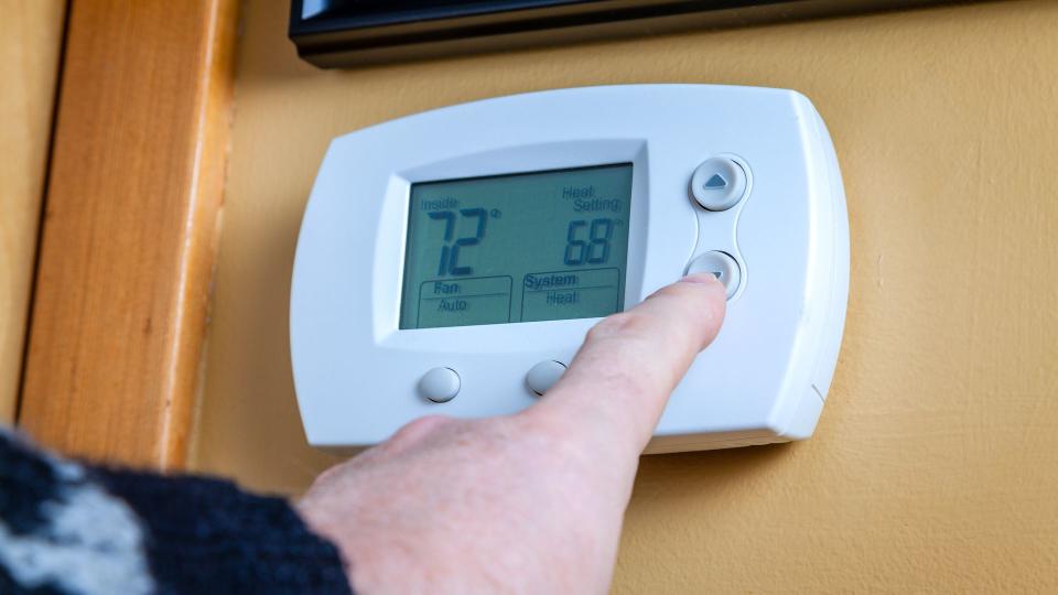 Energy saving, finger on thermostat