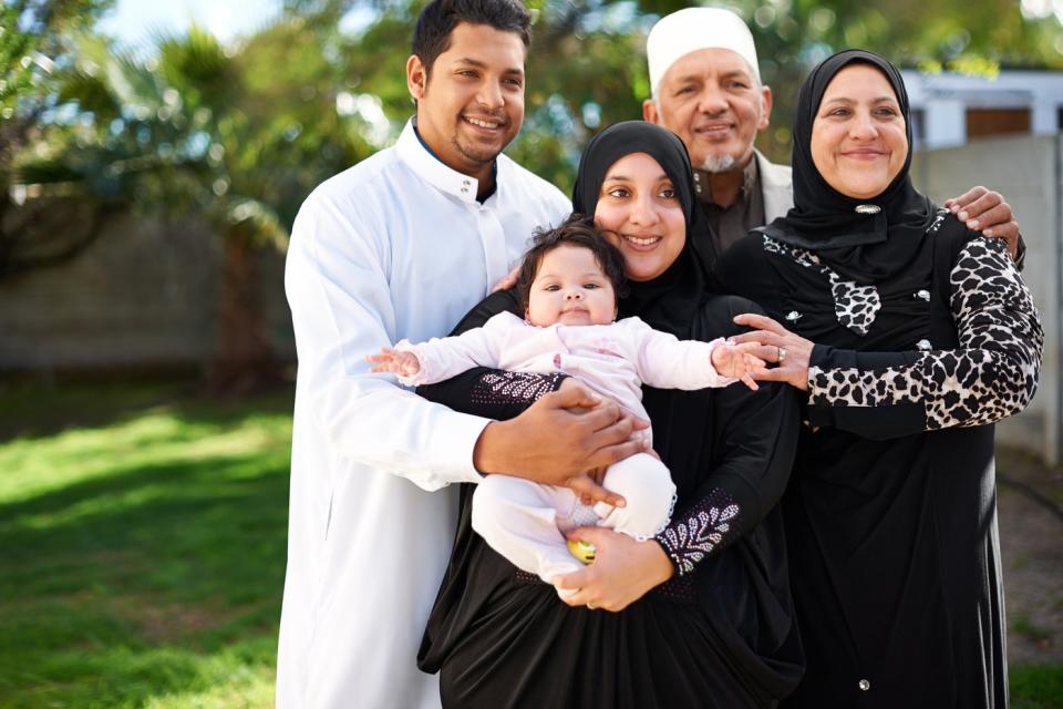 A smiling family standing in a yard. 