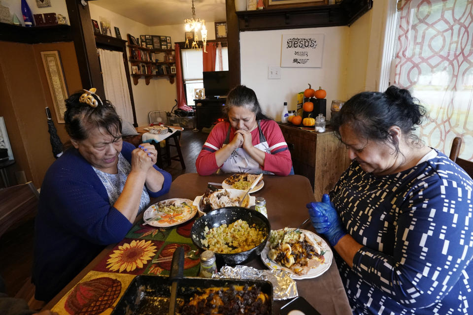 Francis Garcia, left, leads her sisters Anna Garcia, center, and Olga Garcia in prayer at an afternoon family meal Wednesday, Nov. 4, 2020, in the family home in Sedro-Woolley, Wash. On any other Thanksgiving, dozens of Olga's family members would squeeze into her home for the holiday. But this year, she'll deliver food to family spread along 30 miles of the North Cascades Highway in Washington state. If the plan works, everyone will sit down to eat in their own homes at precisely 6:30 p.m. and join a group phone call. (AP Photo/Elaine Thompson)