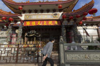 FILE - In this April 2, 2020, file photo, a person walks past the closed Thien Hau Temple in the Chinatown neighborhood of Los Angeles during the coronavirus outbreak. The California Department of Public Health released a framework under which county health departments can approve the reopening of churches, mosques, synagogues and other houses of worship that have mostly shuttered their doors since Gov. Gavin Newsom's March stay-at-home order designed to slow the spread of the coronavirus. California churches can resume in-person services but worshippers will be limited to 100 people and they should wear masks, avoid sharing prayer books and skip the collection plate under state guidelines released Monday, May 25. (AP Photo/Damian Dovarganes, File)