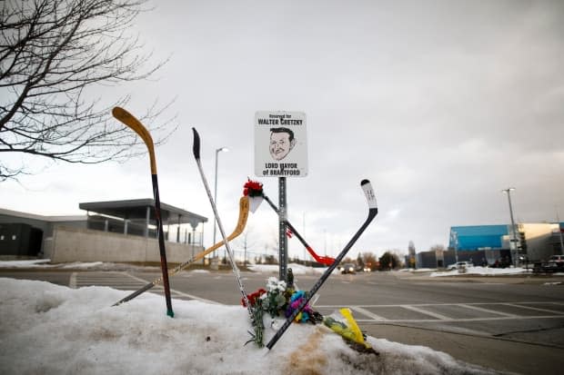 Hockey sticks, cards and flowers are seen on a snowbank beside Walter Gretzky's reserved parking spot at the Wayne Gretzky Sports Centre in Brantford, Ont., on Friday, following news of Walter's death. 