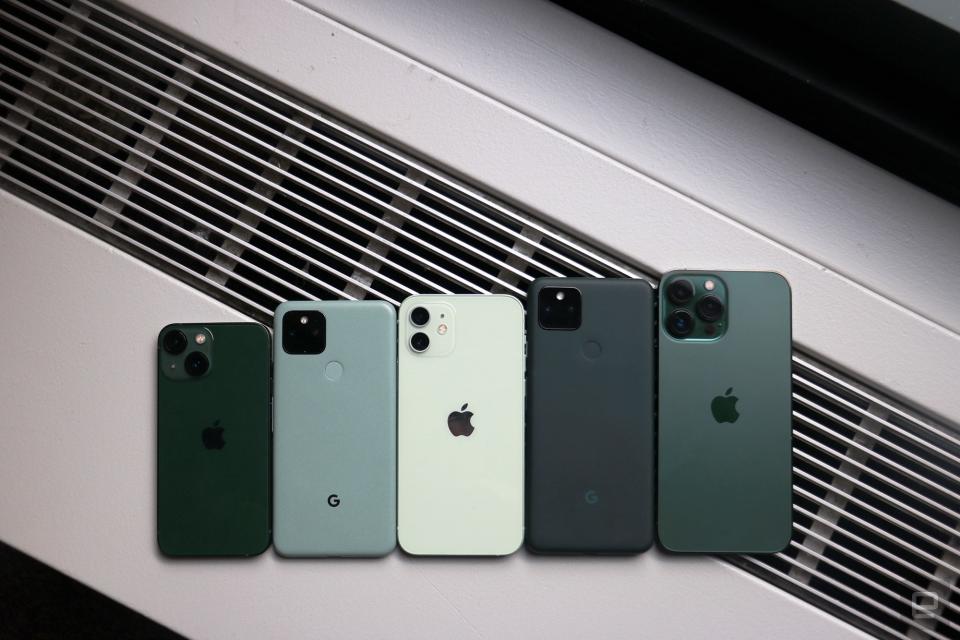 <p>A green iPhone 13 mini, a sage Pixel 5, a green iPhone 12, a dark green Pixel 5a and an "Alpine green" iPhone 13 Pro Max lined up on top of a surface with vents in the background.</p>
