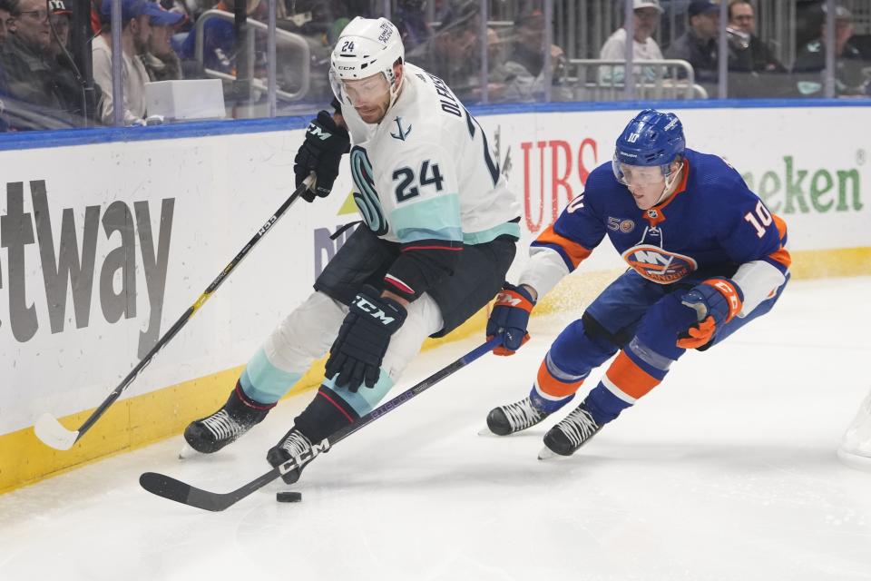 New York Islanders' Simon Holmstrom (10) fights for control of the puck with Seattle Kraken's Jamie Oleksiak (24) during the second period of an NHL hockey game Tuesday, Feb. 7, 2023, in Elmont, N.Y. (AP Photo/Frank Franklin II)