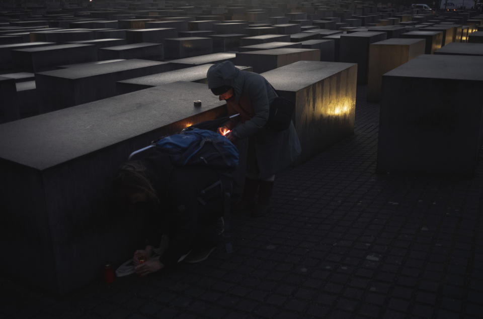 People try to light candles despite strong winds at the Holocaust Memorial at the eve of the International Holocaust Remembrance Day in Berlin, Germany, Friday, Jan. 26, 2024. The International Holocaust Remembrance Day marking the anniversary of the liberation of the Nazi death camp Auschwitz - Birkenau on Jan. 27, 1945. (AP Photo/Markus Schreiber)