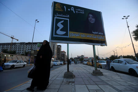 A woman walks past a campaign poster of a candidate ahead of parliamentary election, in Najaf, Iraq, April 20, 2018. Picture taken April 20, 2018. REUTERS/Alaa Al-Marjani