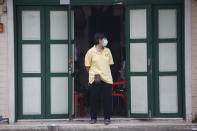A shop assistant wearing a face mask to help curb the spread of the coronavirus stands in front of her shop in Khao San road, a popular hangout for Thais and tourists in Bangkok, Thailand, Monday, April 26, 2021. Cinemas, parks and gyms were among venues closed in Bangkok as Thailand sees its worst surge of the pandemic. A shortage of hospital beds, along with a failure to secure adequate coronavirus vaccine supplies, have pushed the government into imposing the new restrictions. (AP Photo/Anuthep Cheysakron)