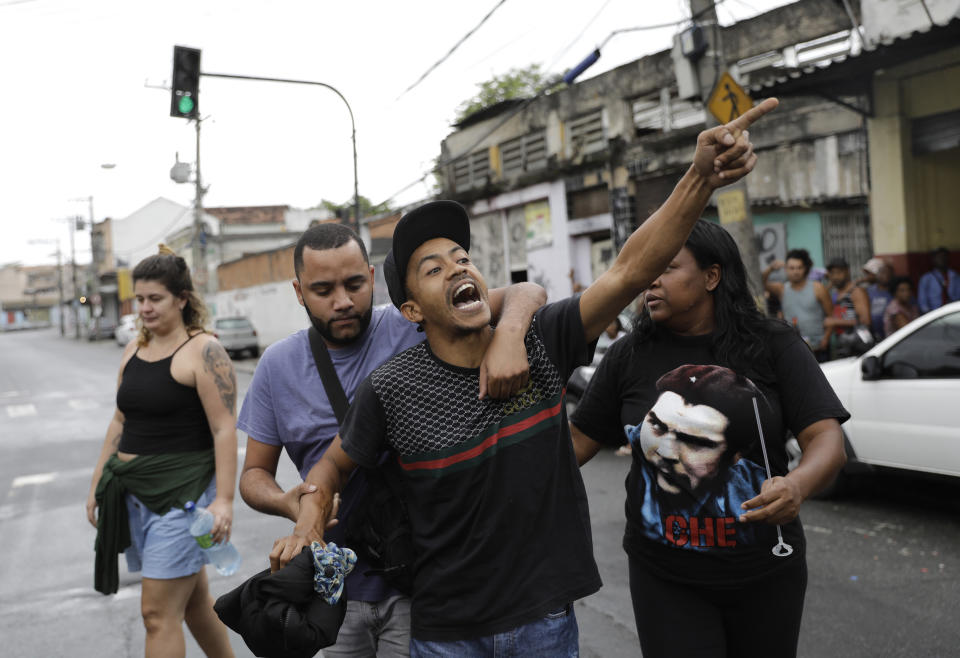 A man shouts at nearby police as he blames the police department for the murder of 8-year-old Ágatha Sales Felix, after her wake, and between the funeral home and the cemetery where she will be buried in Rio de Janeiro, Brazil, Sunday, Sept. 22, 2019. Félix was hit by a stray bullet Friday amid what police said was a shootout with suspected criminals. However, residents say there was no shootout, and blame police. (AP Photo/Silvia Izquierdo)