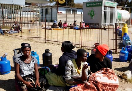 People wait to buy gas at a service station in Harare