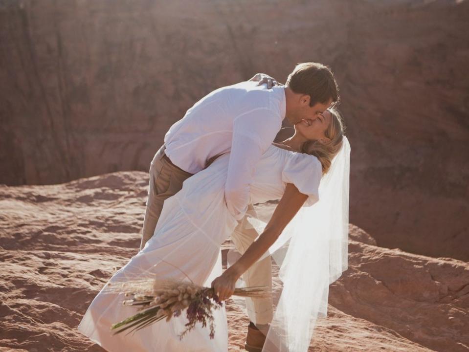 A bride and groom kissing by the canyon