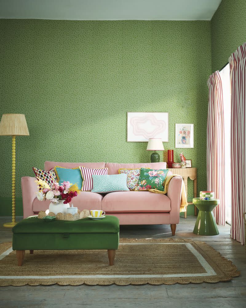 a couch with a table and a lamp in a room with green walls