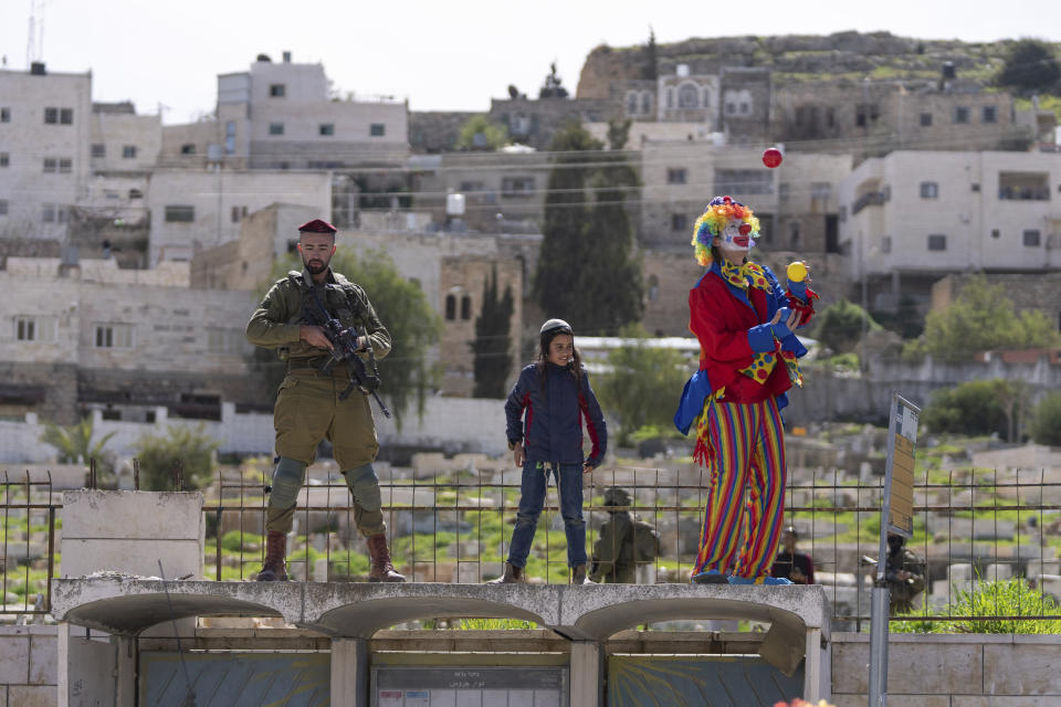 Jewish settlers dressed in costumes celebrate the Jewish holiday of Purim as soldiers secure the march in the West Bank city of Hebron, Tuesday, March 7, 2023. Hebron is a flashpoint city where several hundred hard-line Israeli settlers live in heavily guarded enclaves amid some 200,000 Palestinians. The settlers each year hold a parade on Purim – a Jewish holiday marked by costumes and revelry that commemorates the Jews' salvation from genocide in ancient Persia, as recounted in the biblical Book of Esther. (AP Photo/Ohad Zwigenberg)