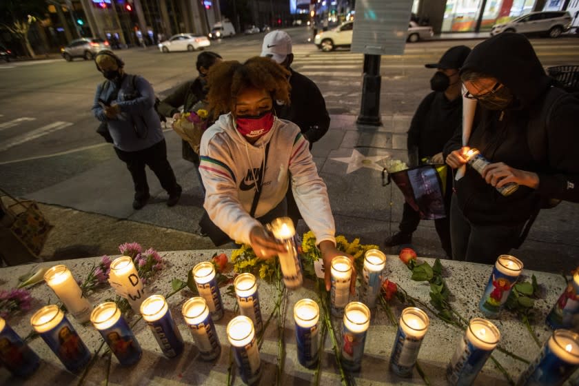 HOLLYWOOD, CA - APRIL 17: Angela Hall, 28, middle, of Los Angeles lights candles on Saturday, April 17, 2021 in Hollywood, CA. A peaceful candlelight vigil and march was held to demand justice for Daunte Wright and Adam Toledo. Wright, 20, was shot and killed on April 11 by a police officer in Brooklyn Center, Minnesota during a traffic stop. Toledo, 13, was shot and killed on March 28 by a police officer in Chicago during a ``shots fired'' investigation. (Francine Orr / Los Angeles )