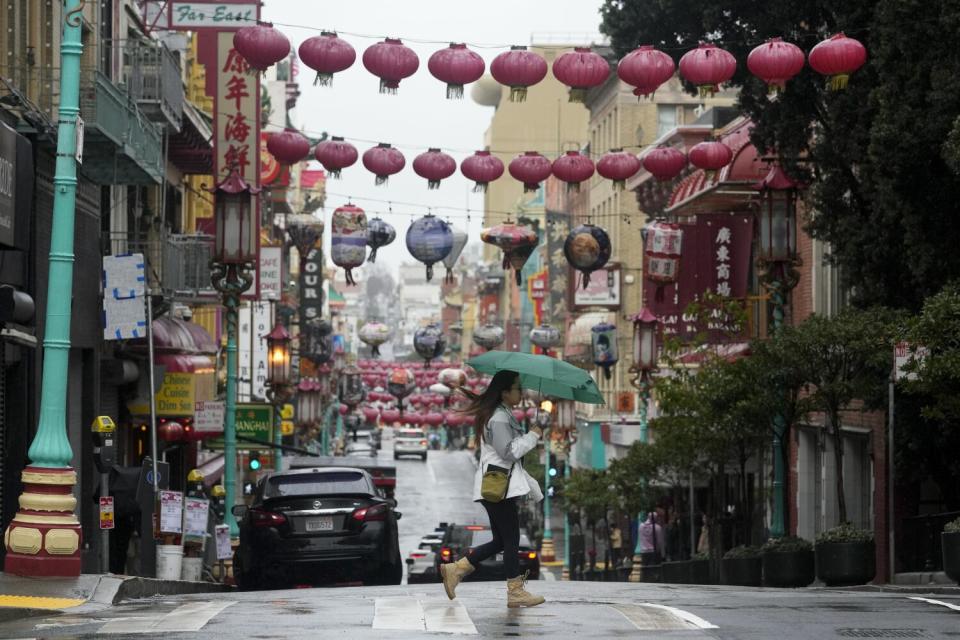 A woman crosses a street in Chinatown in San Francisco.