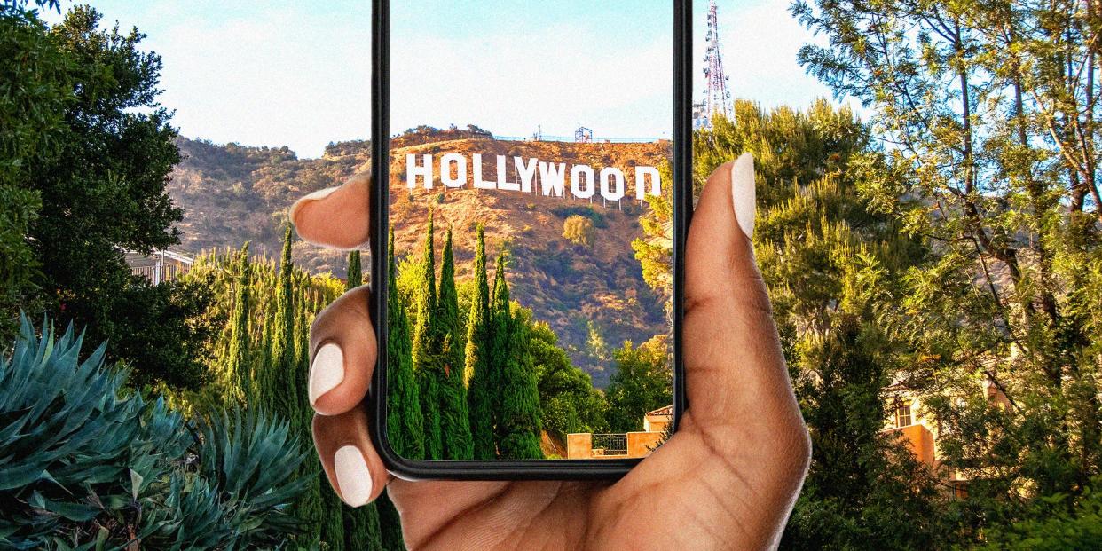 Someone holding a phone up to the Hollywood sign