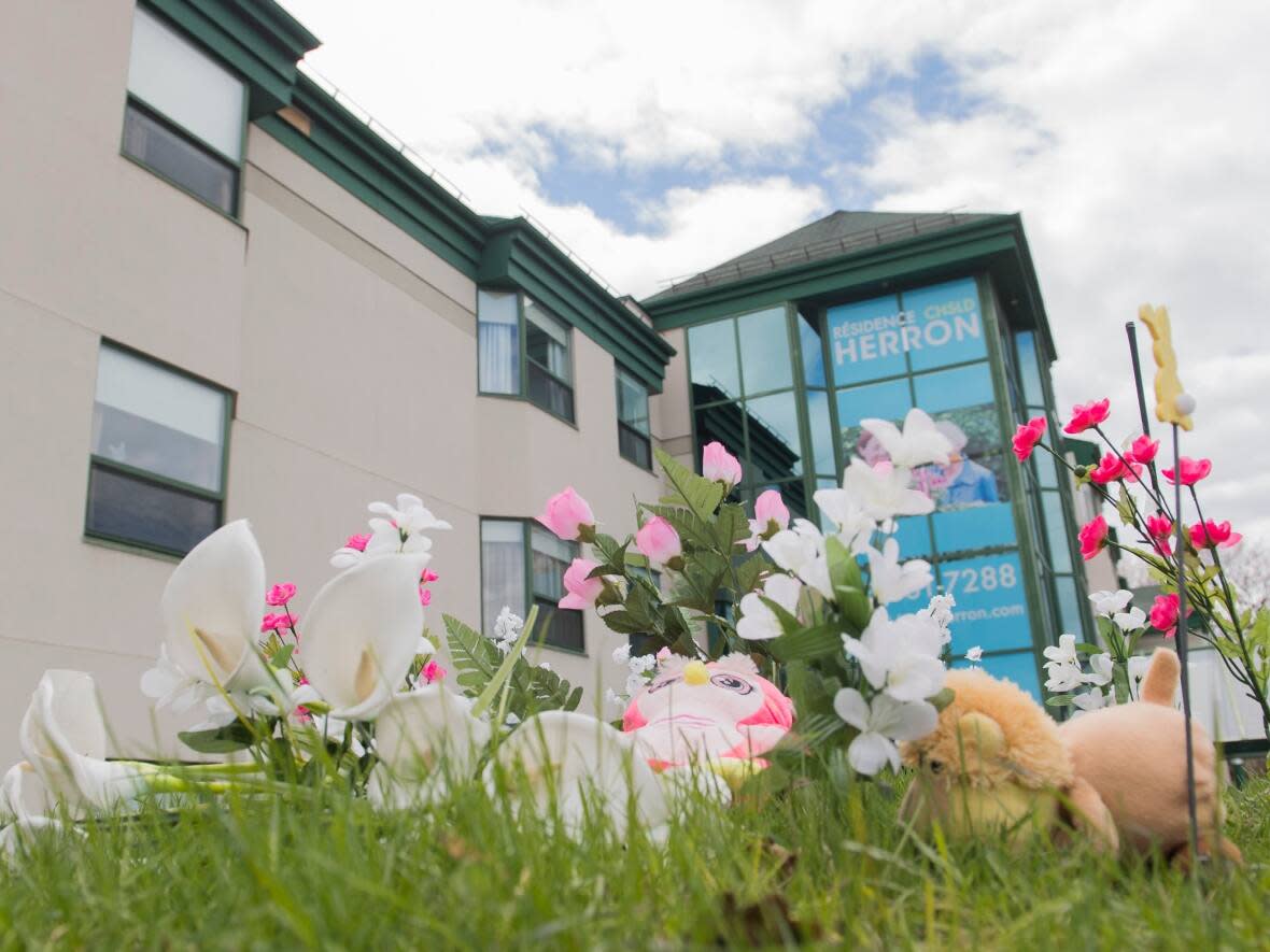 Plush toys and flowers are shown outside the Herron long term care home in May 2020.  Opposition parties and some family members of those who died in care homes are increasing the pressure on the Legault government to launch a full public inquiry. (Graham Hughes/The Canadian Press - image credit)