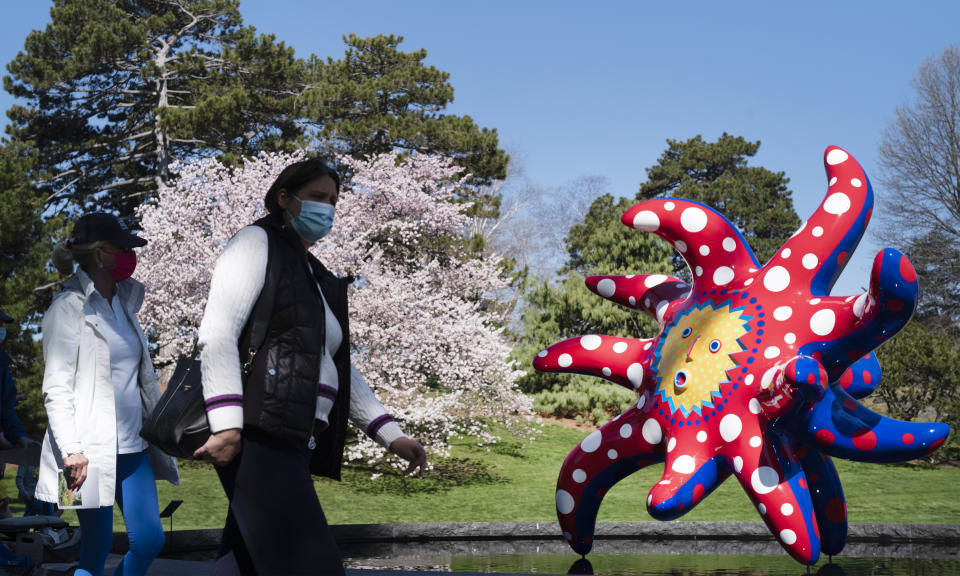 People walk by the sculpture "I Want to Fly to the Universe" by Japanese artist Yayoi Kusama at the New York Botanical Garden, Thursday, April 8, 2021 in the Bronx borough of New York. The expansive exhibit has opened, and ticket sales have been brisk in a pandemic-weary city hungry for more outdoor cultural events. (AP Photo/Mark Lennihan)