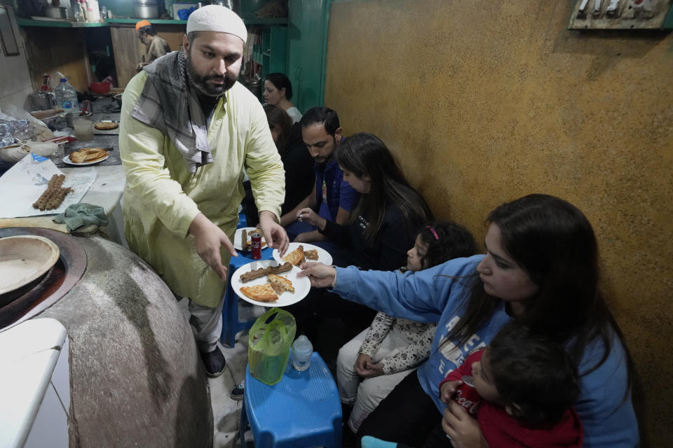 Bilal Sufi, left, owner of Baking Virsa eatery, serves traditional kebabs and naan bread in Lahore, Pakistan, Saturday, Dec. 3, 2022. No menu. Baking Virsa, a hole-in-the-wall in the eastern Pakistani city of Lahore described as the country's most expensive restaurant for serving household favorites like flatbreads and kebabs at exorbitant prices. (AP Photo/K. M. Chaudary)