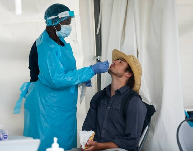 A visitor to Nashville North has a rapid COVID test at the Calgary Stampede in Calgary on July 9. At least 84 cases of COVID-19 have been directly linked to the festival.  (Jeff McIntosh/Canadian Press - image credit)