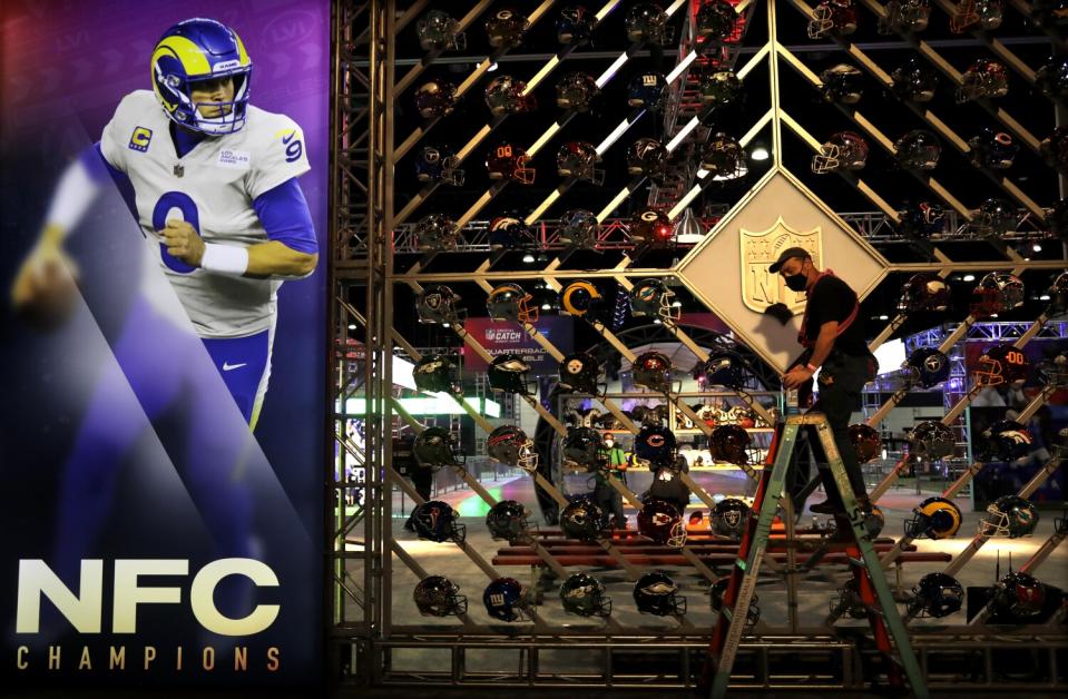 A man on a ladder prepares a display of football helmets