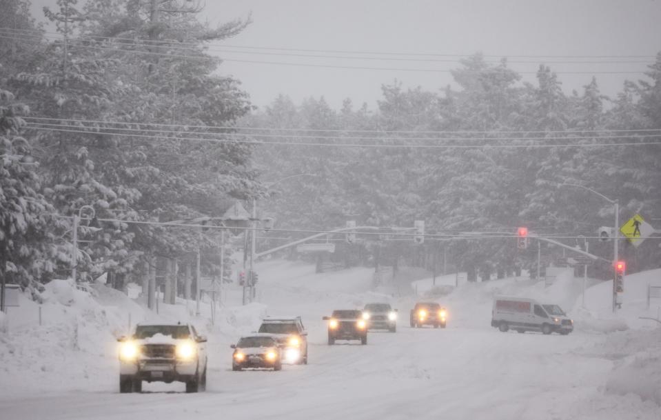 Vehicles drive as snow falls during another winter storm in the Sierra Nevada mountains on March 10, 2023 in Mammoth Lakes, California.