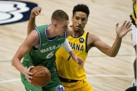 Dallas Mavericks center Kristaps Porzingis (6) works against Indiana Pacers guard Malcolm Brogdon (7) for a shot during the first half of an NBA basketball game in Dallas, Friday, March 26, 2021. (AP Photo/Tony Gutierrez)