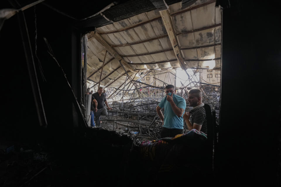 People gather at the site of a fatal fire, in the district of Hamdaniya, Nineveh province, Iraq, Thursday, Sept. 28, 2023. A fire that raced through a hall hosting a Christian wedding in northern Iraq killed multiple people, authorities said. (AP Photo/Hadi Mizban)