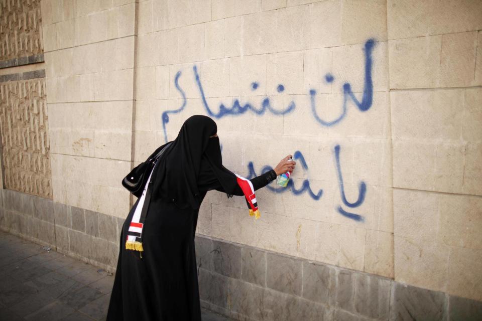 A woman writes 'We won't forget you, oh our martyrs' on a wall in Sanaa, Yemen during a 2013 protest demanding an end to the violence which consumed the country after the Arab Spring: Reuters