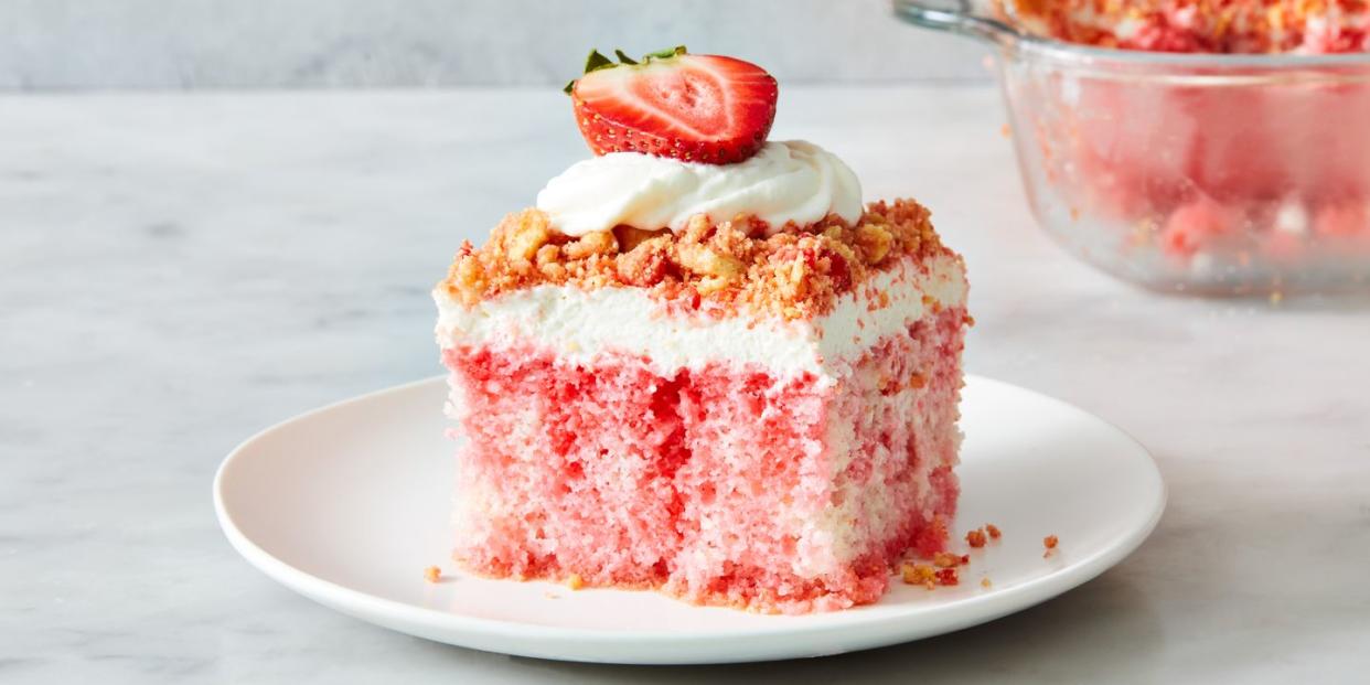 strawberry crunch poke cake with a crumble topping, whipped cream and strawberries