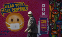 A man walks past a mural on how to wear a face mask to prevent the spread of coronavirus, in Soweto, South Africa, Saturday, May 15, 2021. (AP Photo/Themba Hadebe)