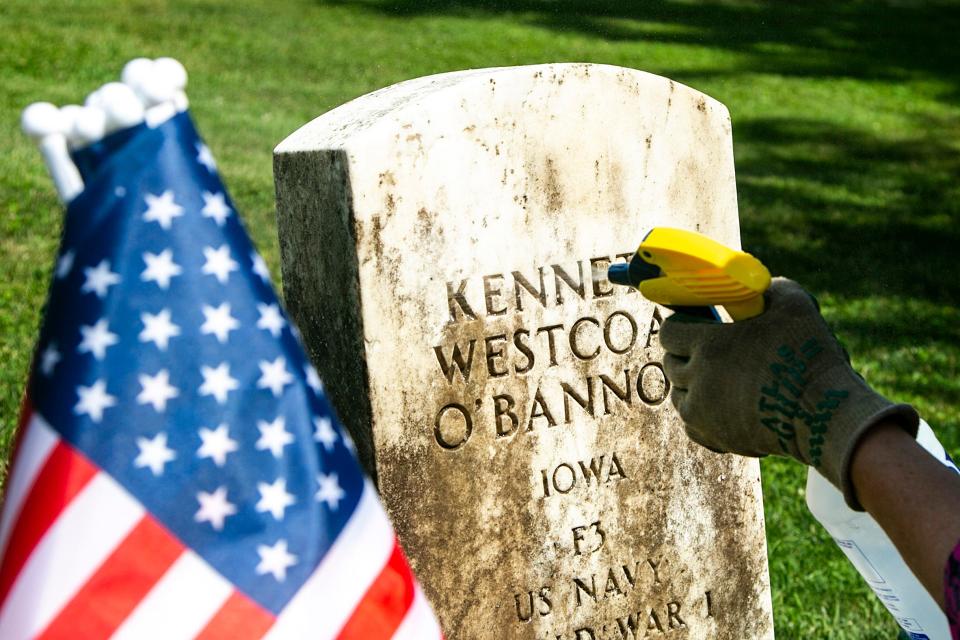 Madonna White cleans the headstone of a World War I veteran, Tuesday, July 12, 2022, at Oakland Cemetery in Iowa City, Iowa.