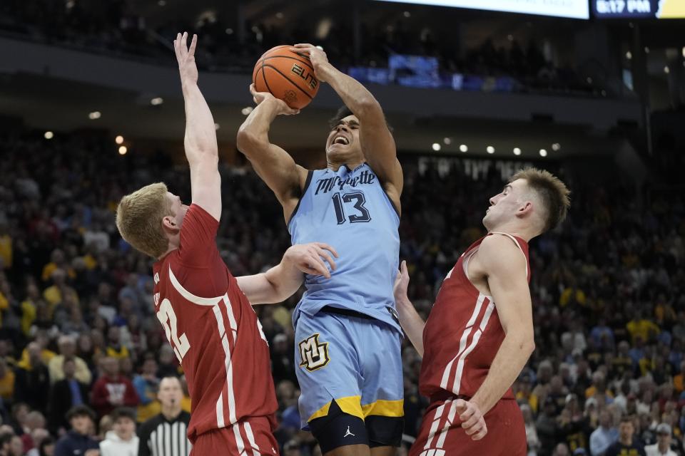 Marquette's Oso Ighodaro is fouled driving between Wisconsin's Steven Crowl and Tyler Wahl during the second half of an NCAA college basketball game Saturday, Dec. 3, 2022, in Milwaukee. Wisconsin won 80-77 in overtime. (AP Photo/Morry Gash)