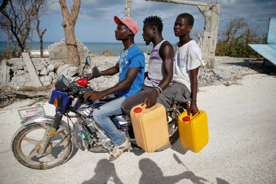 <p>Men ride a motorcycle in front of destroyed houses after Hurricane Matthew passes Jeremie, Haiti, October 7, 2016. (REUTERS/Carlos Garcia Rawlins)</p>