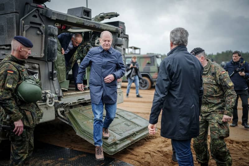 Germany's Chancellor Olaf Scholz climbs out of a Boxer wheeled armored vehicle next to Lithuanian President Gitanas Naueda during a visit to the NATO exercise Quadriga 24. Kay Nietfeld/dpa