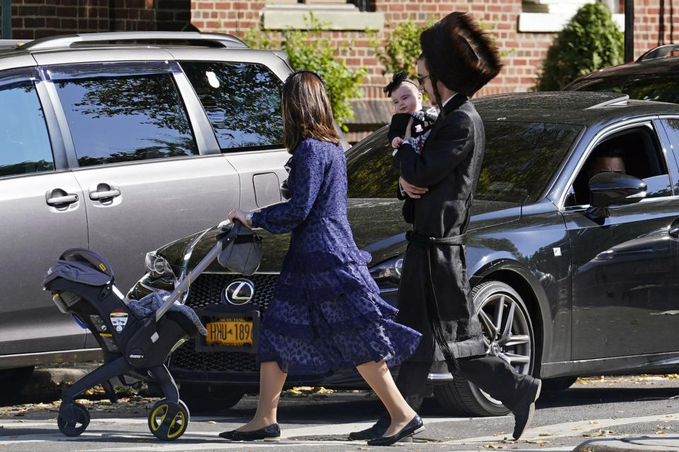 FILE - In this Oct. 4, 2020, file photo, an Orthodox Jewish family crosses a street during the Jewish holiday of Sukkot in the Borough Park neighborhood in the Brooklyn borough of New York. Amid a new surge of COVID-19 in New York’s Orthodox Jewish communities, many residents are reviving health measures that some had abandoned over the summer – social distancing, wearing masks. For many, there’s also a return of anger: They feel the city is singling them out for criticism that other groups avoid. (AP Photo/Kathy Willens, File)